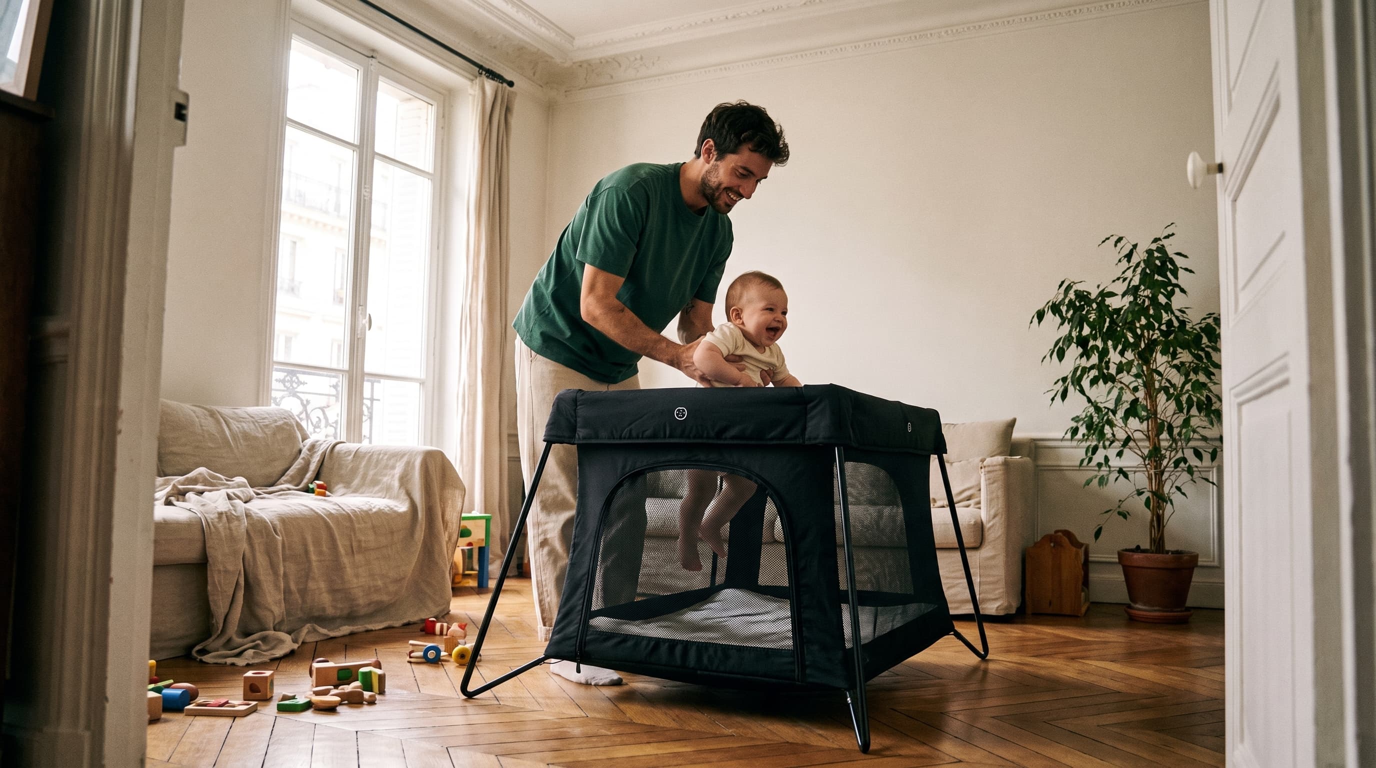 Père et bébé avec un lit parapluie dans un appartement parisien